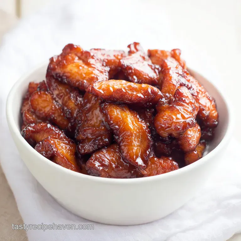 Glazed chicken pieces arranged on a ceramic plate with steamed rice, sliced scallions, and toasted sesame seeds.